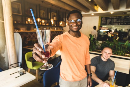 Meet young attractive people in the cafe. Friends chat, have fun, drink cocktails and eatの写真素材