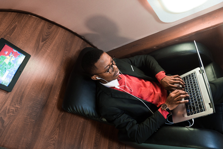 Attractive and successful African American businessman with glasses working on a laptop while...