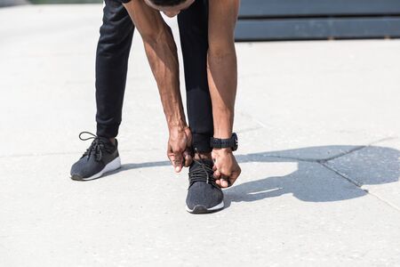 Athletic young afroamerican runner doing warm up on the promenade. Black Male running on outdoors....