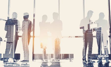 Silhouettes of people against the window. A team of young businessman working and communicating together in an office. Corporate business team and manager in a meeting.の写真素材