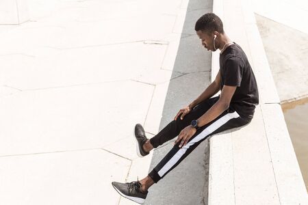 Athletic young afroamerican runner doing warm up on the promenade. Black Male running on outdoors. Healthy lifestyle concept.の写真素材