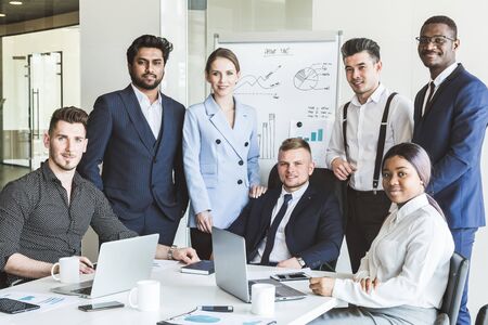 A team of young businessmen stand shoulder to shoulder, working and communicating together in an office. Corporate businessteam and manager in a meeting.の写真素材