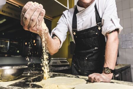 Professional chef cooking in the kitchen restaurant at the hotel, preparing dinner. A cook in an apron makes a salad of vegetables and pizzaの写真素材