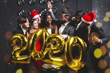 Beautiful young people at a corporate party holding balloons 2020. Happy New Year celebration. Club party with friendsの写真素材