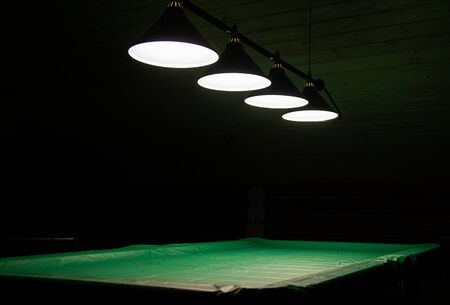 Pool table lit by lamps on a dark background. Low key shooting in low lightの写真素材