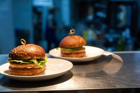 Ready meals hamburgers at the counter for delivery to waiters in a restaurant and kitchen in the background.の写真素材