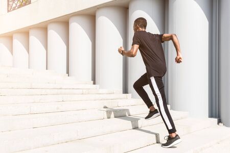 Athletic young afroamerican man running on the promenade. Black Male runner sprinting outdoors....