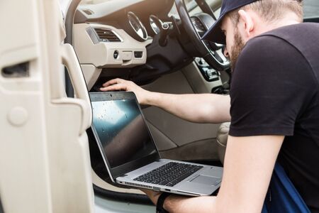 Professional car mechanic working in auto repair service. Computer video investigate. Engine...