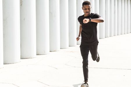 Athletic young afroamerican man running on the promenade. Black Male runner sprinting outdoors....