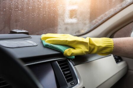 Cleaning service. Man in uniform and yellow gloves washes a car interior in a car wash.