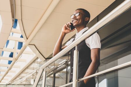 Young african american business man in suit and eyeglasses talking on the phone on the background of the business centerの写真素材