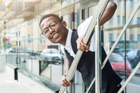 Young african american business man in suit and eyeglasses talking on the phone on the background of the business centerの写真素材