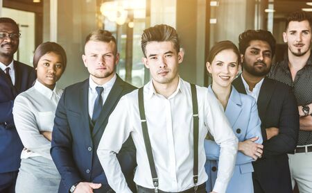 A team of young businessmen stand shoulder to shoulder, working and communicating together in an...