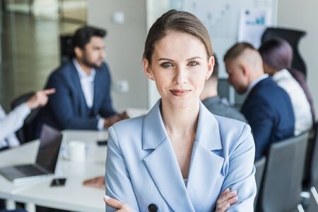Business woman stands on the background of partners. A team of young businessmen working and communicating together in an office. Corporate businessteam and manager in a meetingの写真素材
