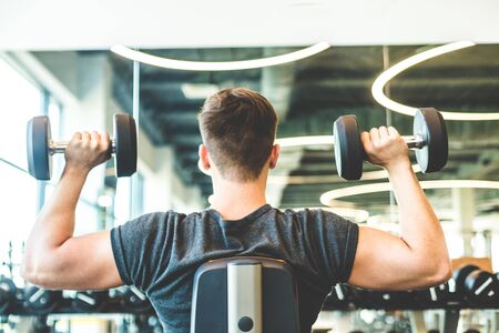 Working out with dumbbell weights at the gym.Fitness men exercising are lifting dumbbells. Fitness muscular body. Workout at gymの写真素材