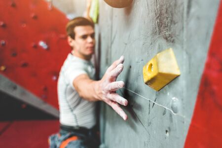 Sportsman climber moving up on steep rock, climbing on artificial wall indoors. Extreme sports and bouldering conceptの写真素材