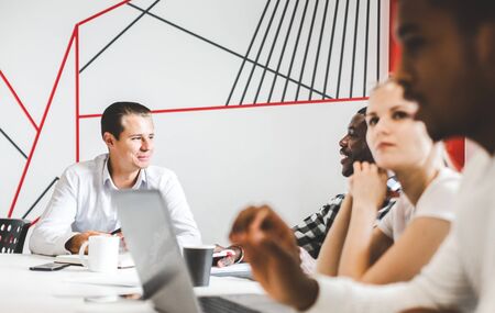 A team of young office workers, businessmen with laptop working at the table, communicating together in an office. Corporate businessteam and manager in a meeting. coworking.の写真素材