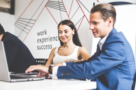 A team of young office workers, businessmen with laptop working at the table, communicating together in an office. Corporate businessteam and manager in a meeting. coworking.の写真素材