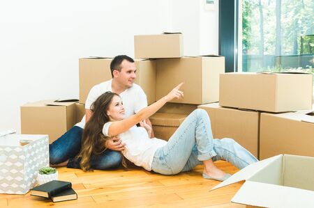 Happy young family, parents daughter and son, unpacking boxes and moving into a new home. funny kids run in with boxesの写真素材