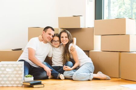 Happy young family, parents daughter and son, unpacking boxes and moving into a new home. funny kids...