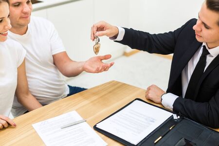 real estate agent is selling an apartment to a young family. conclusion of a lease and purchase of a house, apartment. man shows housingの写真素材