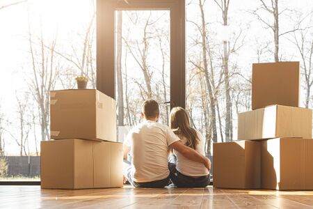 young couple moves to a new home. the family carries boxes of things after buying a home