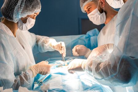 An international team of doctors performs a complex surgical operation on a patient under...