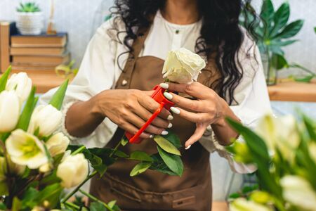 Attractive young woman florist is working in a flower shop. pruning flower stems