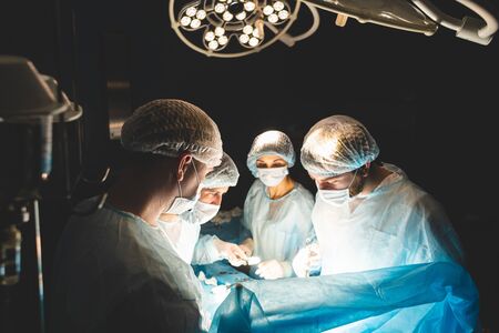 The senior surgeon in the operating room, where the patient is waiting for him, and he begins the operation. Real Modern Hospital with Authentic Equipmentの写真素材