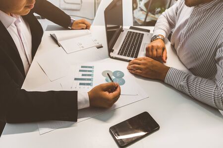 Young office worker sitting at desk, using computer. Two business man talking.の写真素材
