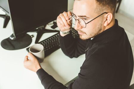 Young office worker sitting at desk, using computer. Two business man talking.の写真素材