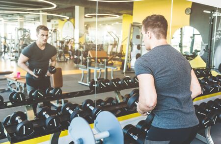Working out with dumbbell weights at the gym.Fitness men exercising are lifting dumbbells. Fitness...