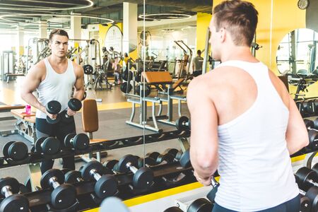 Working out with dumbbell weights at the gym.Fitness men exercising are lifting dumbbells. Fitness muscular body. Workout at gym.の写真素材