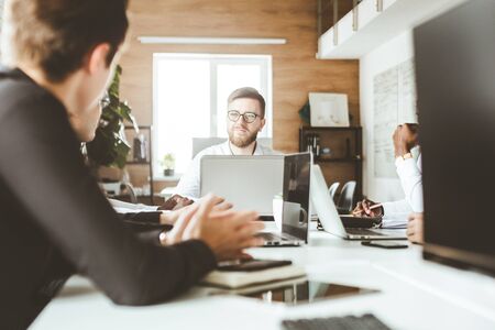 A team of young businessmen working and communicating together in an office. Corporate businessteam and manager in a meeting.の写真素材