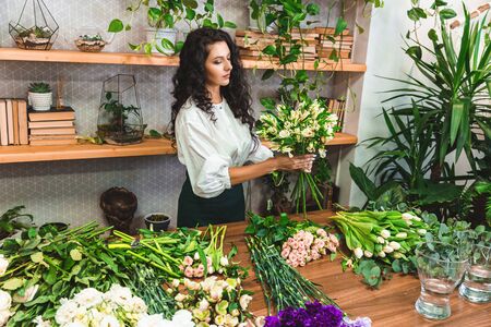 Attractive young woman florist is working in a flower shop.の写真素材