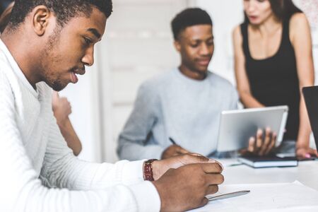 A team of young office workers, businessmen with laptop working at the table, communicating together in an office. Corporate businessteam and manager in a meeting. coworking.の写真素材