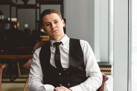 Portrait of a young successful businessman in a suit in the office. Close-up sitting in a chair by the windowの写真素材