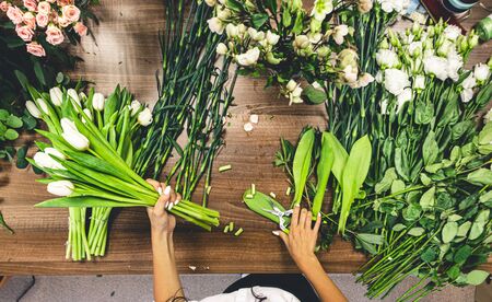 Flower shop. A woman seller sorts and collects bouquets of many fresh flowers. Top view on counter.の写真素材