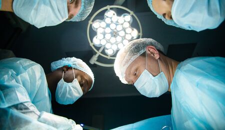 The faces of doctors in medical masks from the bottom up during a surgical operation