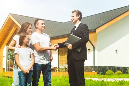 real estate agent is selling an apartment to a young family. conclusion of a lease and purchase of a house, apartment. man shows housingの写真素材