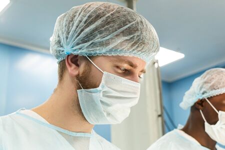Portrait of a doctor during surgery in a uniform and medical maskの写真素材