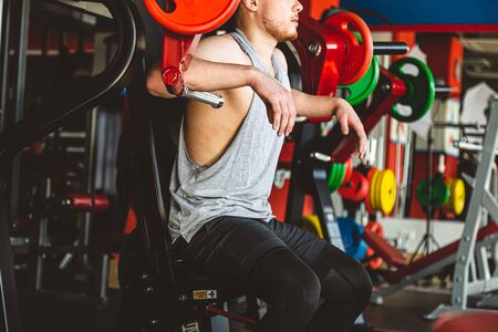 The young athlete does exercises in the gym. Power approaches on the simulatorの写真素材