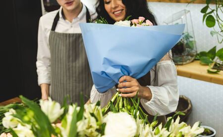 An attractive, experienced female florist teaches a young man how to work in a flower shop.の写真素材