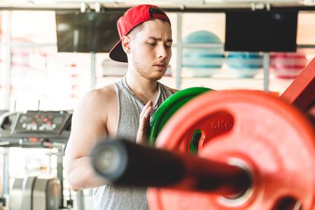 Strength training of a muscular young athlete in the gym. Stamina and perseverance