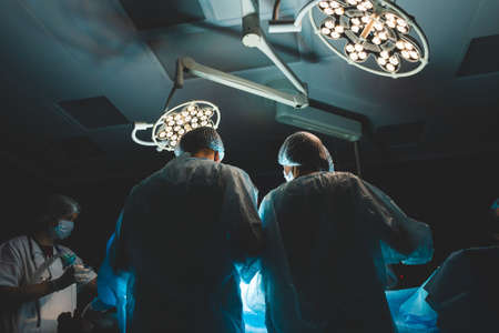 The senior surgeon in the operating room, where the patient is waiting for him, and he begins the operation. Real Modern Hospital with Authentic Equipmentの写真素材