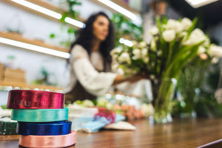 Attractive young woman florist is working in a flower shop.