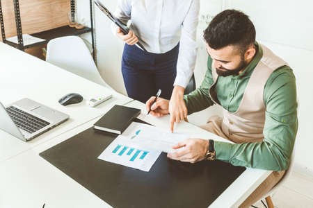 Secretary and Chief signs papers. A team of young businessmen working and communicating together in an office. Corporate businessteam and manager in a meeting.の写真素材
