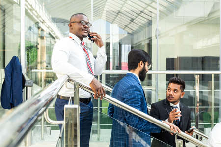 young business people arego down the stairs and talking on the background of glass offices. Corporate businessteam and manager in a meeting.の写真素材