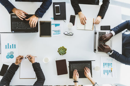 Group of young business people working and communicating while sitting at the office desk together...