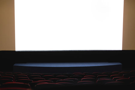 Cinema interior. Chairs in a large empty cinema hall against a white projection screenの写真素材